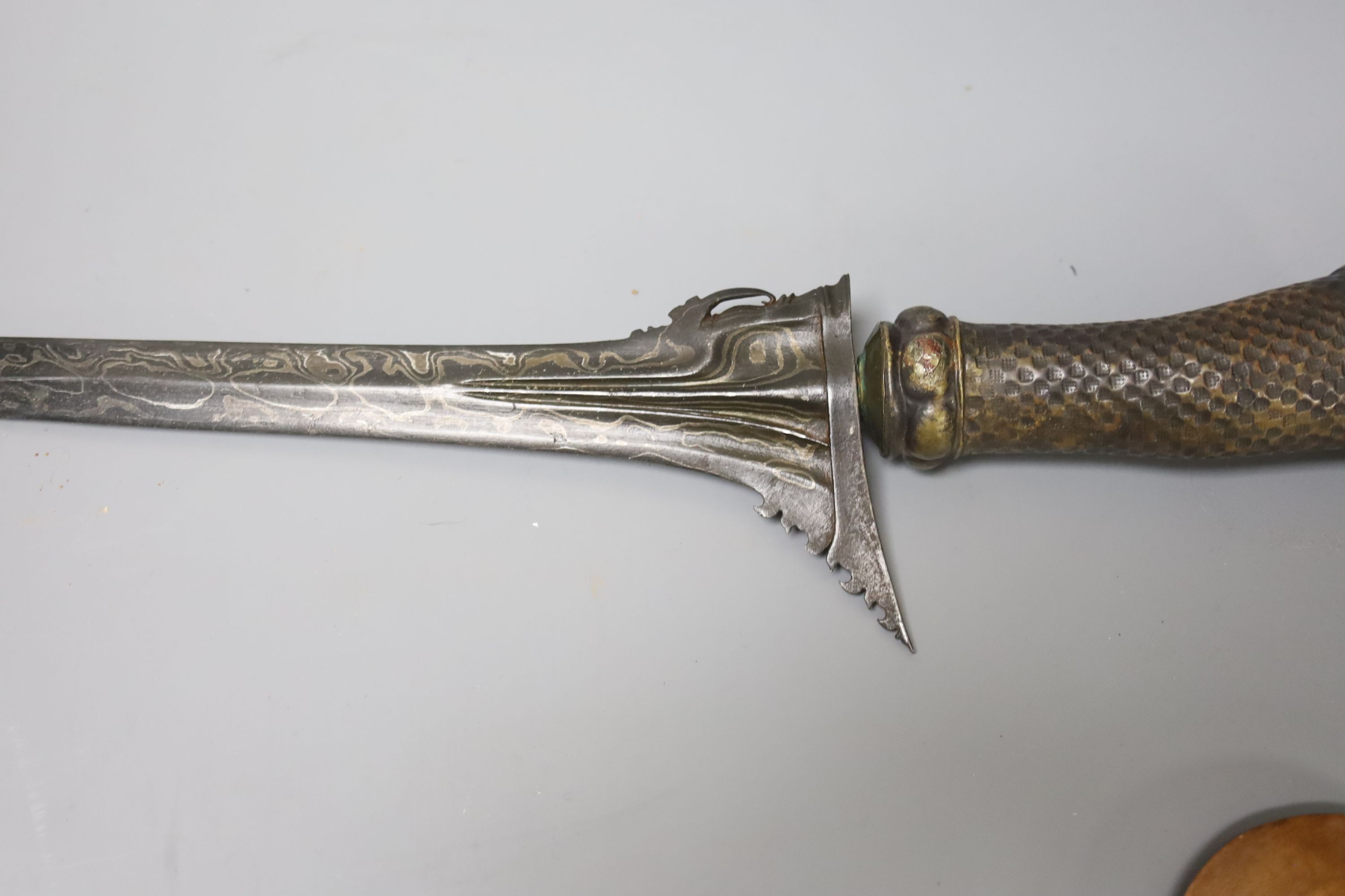 An Indonesian dagger kris, 19th century, earlier black and silver-coloured watered blade, brass hilt, wooden scabbard, blade 33cms